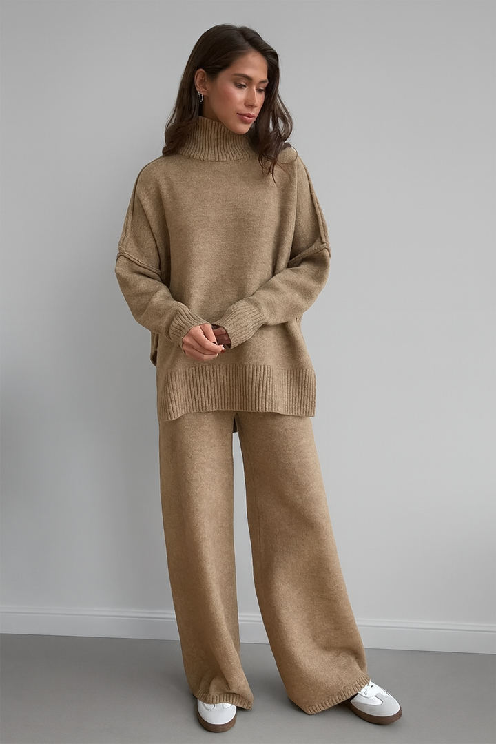 Woman wearing a beige sweater and pants set against a gray background