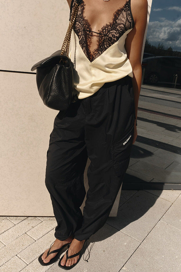Person wearing a white top with lace detail and black pants, standing outdoors.