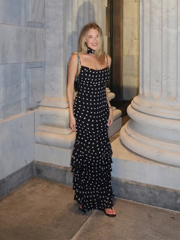 Woman in a black and white polka dot dress standing in a marble interior setting.