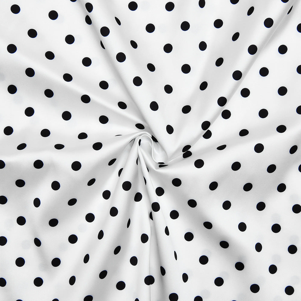 White fabric with black polka dots, folded in a way that creates a circular pattern.