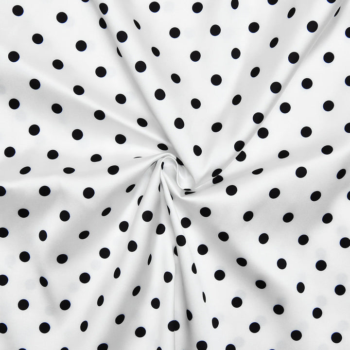 White fabric with black polka dots, folded in a way that creates a circular pattern.