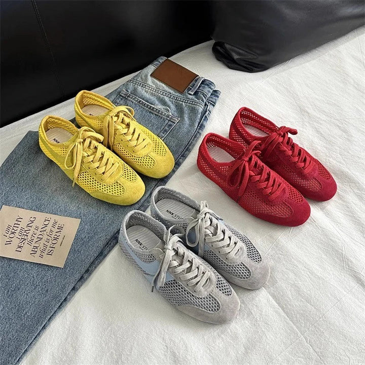 Three pairs of sneakers in yellow, red, and gray on a white surface with jeans.