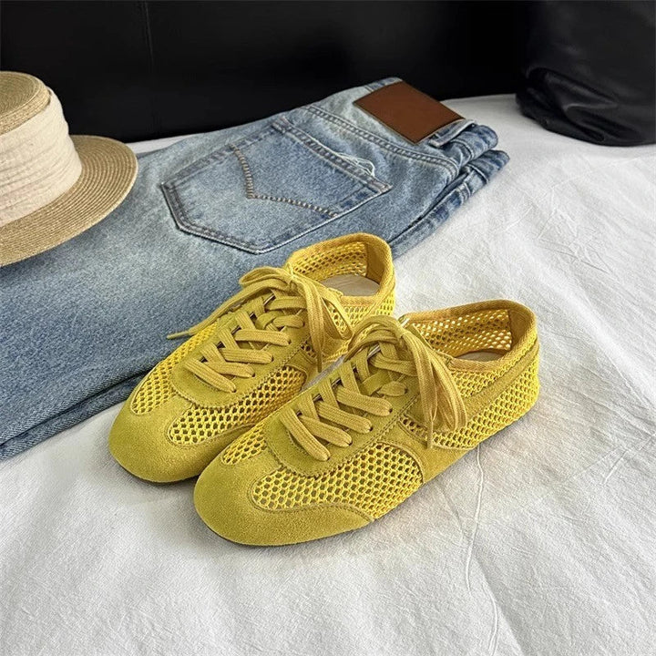 Yellow sneakers with a hat and jeans on a white surface